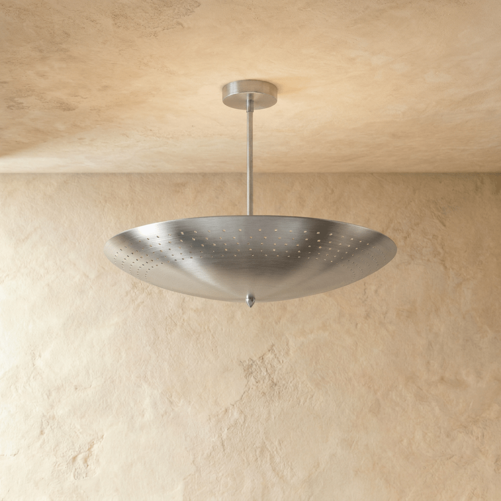 Clérachic perforated disc pendant light in chrome, hung from a plaster ceiling and photographed in studio.