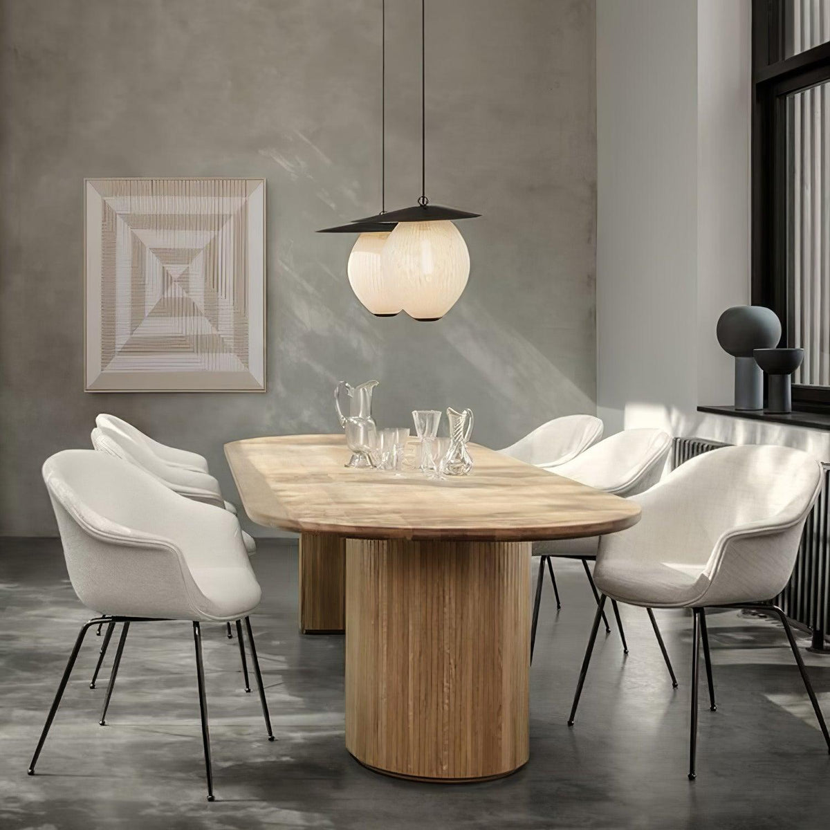 Clérachic pleated mesh pendant lamps in ivory hung as a pair over an oak dining table in a concrete-walled room.