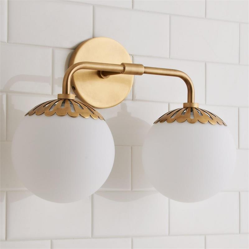 Two-head Clérachic Petal-Cap Opal Globe Wall Sconce in brass, twin opal globes on a slim curved arm over white tile.