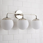 Three-head Clérachic Petal-Cap Opal Globe Wall Sconce in polished nickel, globes lined up on a tiled wall.