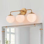 Lit brass Clérachic Petal-Cap Opal Globe Wall Sconce with three heads above a grey linen-framed mirror.