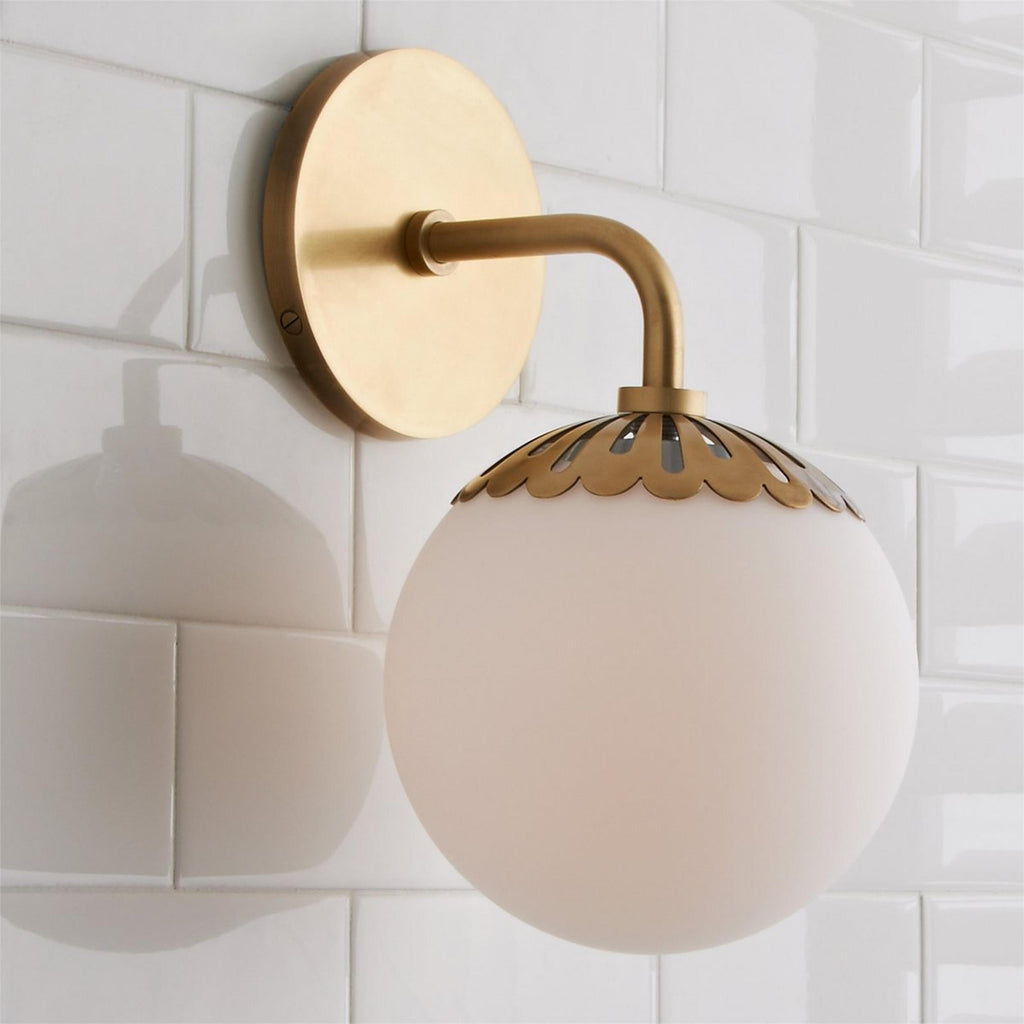 Close-up of the brass Clérachic Petal-Cap Opal Globe Wall Sconce showing the teardrop cut-outs in the collar.