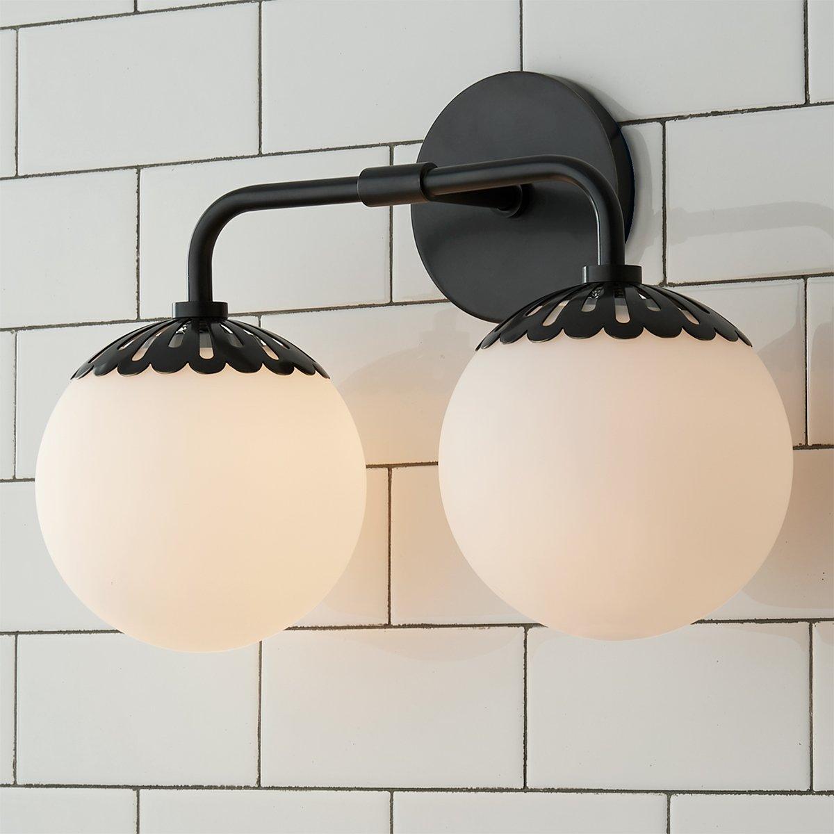 Two-head black Clérachic Petal-Cap Opal Globe Wall Sconce at three-quarters, one globe nearer the camera.