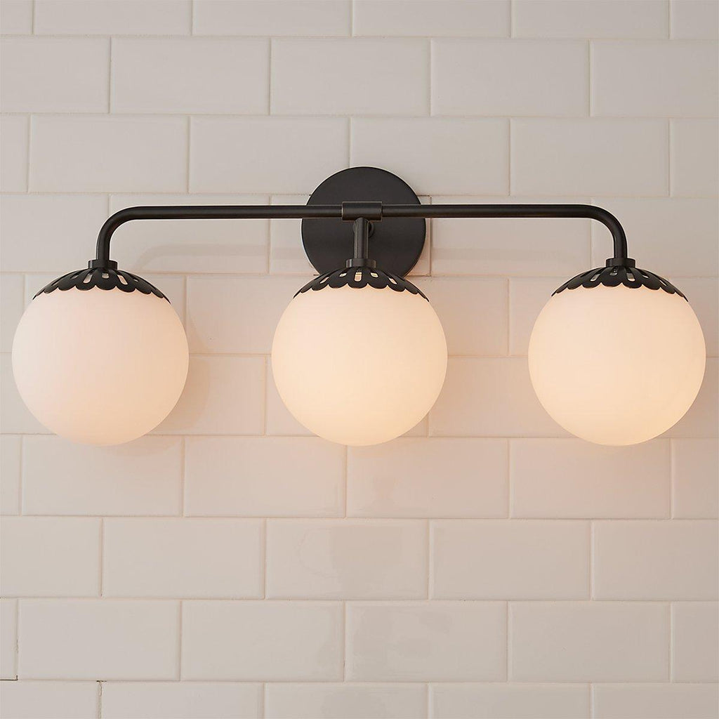 Head-on three-head black Clérachic Petal-Cap Opal Globe Wall Sconce, globes evenly spaced under petal caps.