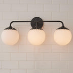 Head-on three-head black Clérachic Petal-Cap Opal Globe Wall Sconce, globes evenly spaced under petal caps.