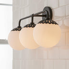 Side view of the three-head black Clérachic Petal-Cap Opal Globe Wall Sconce, globes receding toward a window.