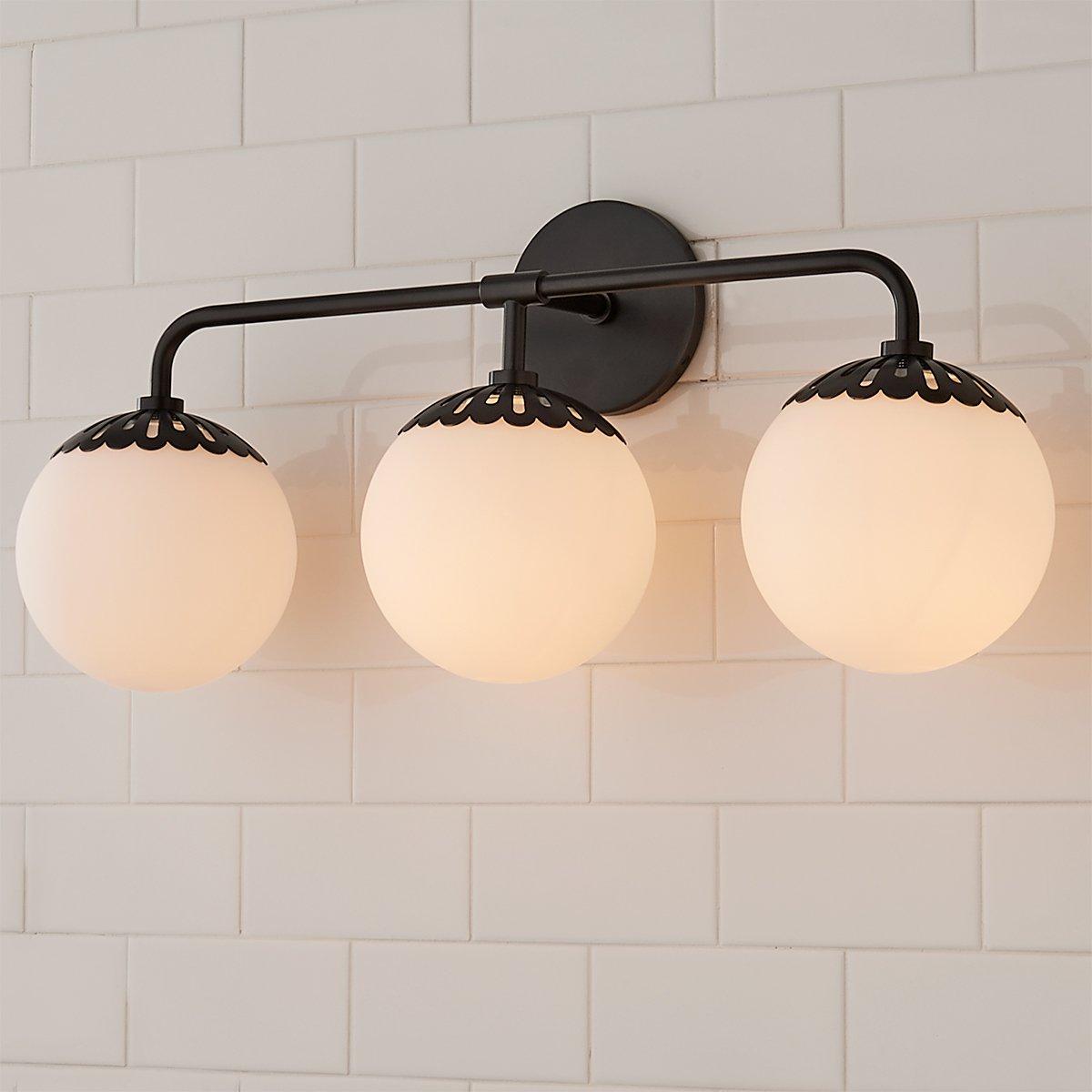Three-head black Clérachic Petal-Cap Opal Globe Wall Sconce seen slightly from below on white tile.