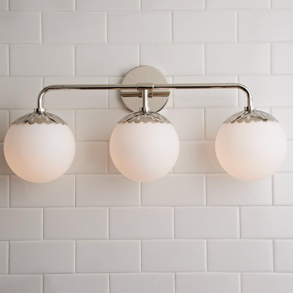 Three-head nickel Clérachic Petal-Cap Opal Globe Wall Sconce head-on, arm and caps mirroring the tile.
