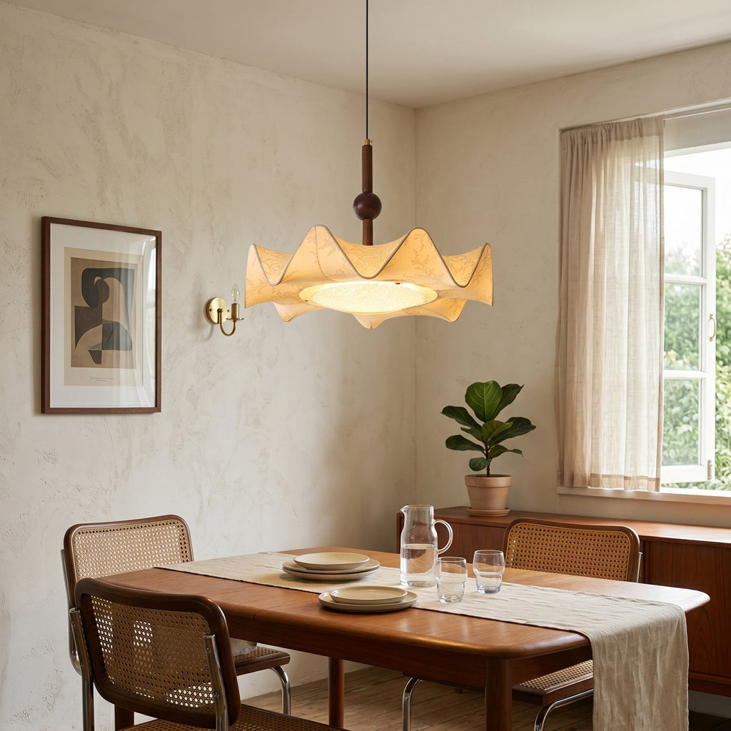 Beside a window with sheer curtains, this Clérachic pendant hangs over a wooden dining table set with plates, a jug and glasses.
