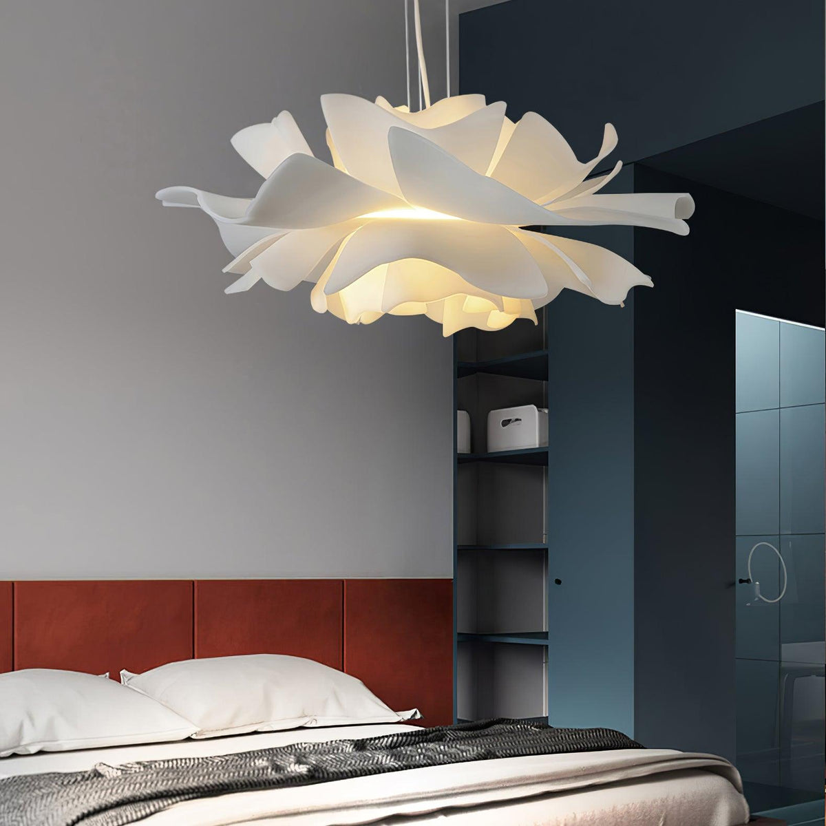 Clérachic flower pendant above a bed with a rust-red headboard, beside blue-grey open shelving and a glass partition.