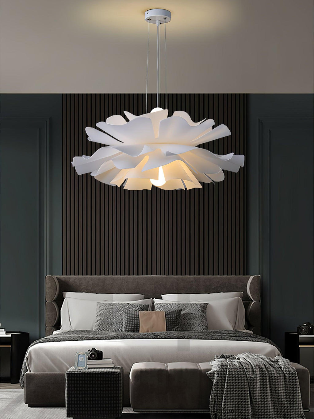 Clérachic bloom pendant above a grey bed set against a charcoal slat wall, with a camera on the end bench.