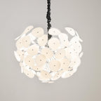 Close crop of the lit Clérachic Petal Sphere Chandelier glowing warm ivory, its black ruched cord above.