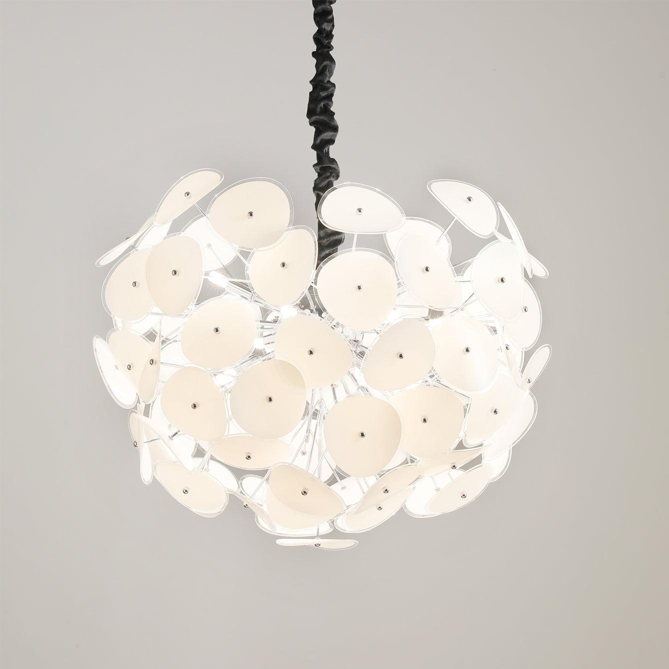 Close crop of the lit Clérachic Petal Sphere Chandelier glowing warm ivory, its black ruched cord above.
