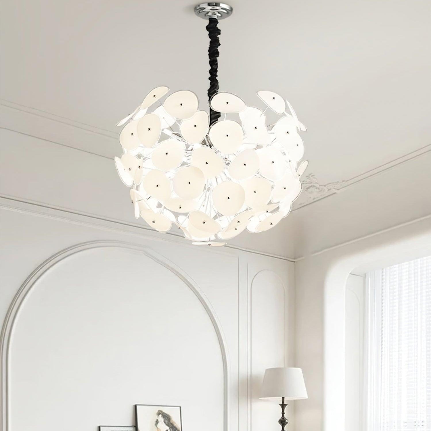Lit Clérachic Petal Sphere Chandelier hung above an arched doorway in a room with crown moulding and a window.