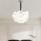 Lit Clérachic Petal Sphere Chandelier beside a window with pleated cellular blinds and a framed chair-design poster.