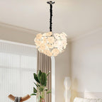 Lit Clérachic Petal Sphere Chandelier in a living room with a green velvet armchair and an artist's easel.