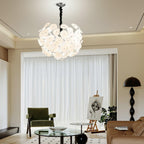Lit Clérachic Petal Sphere Chandelier above a leather sofa, facing a gallery wall with a framed chess print.