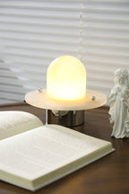 The Clérachic Petrified lamp lit warm on a walnut table beside an open book.