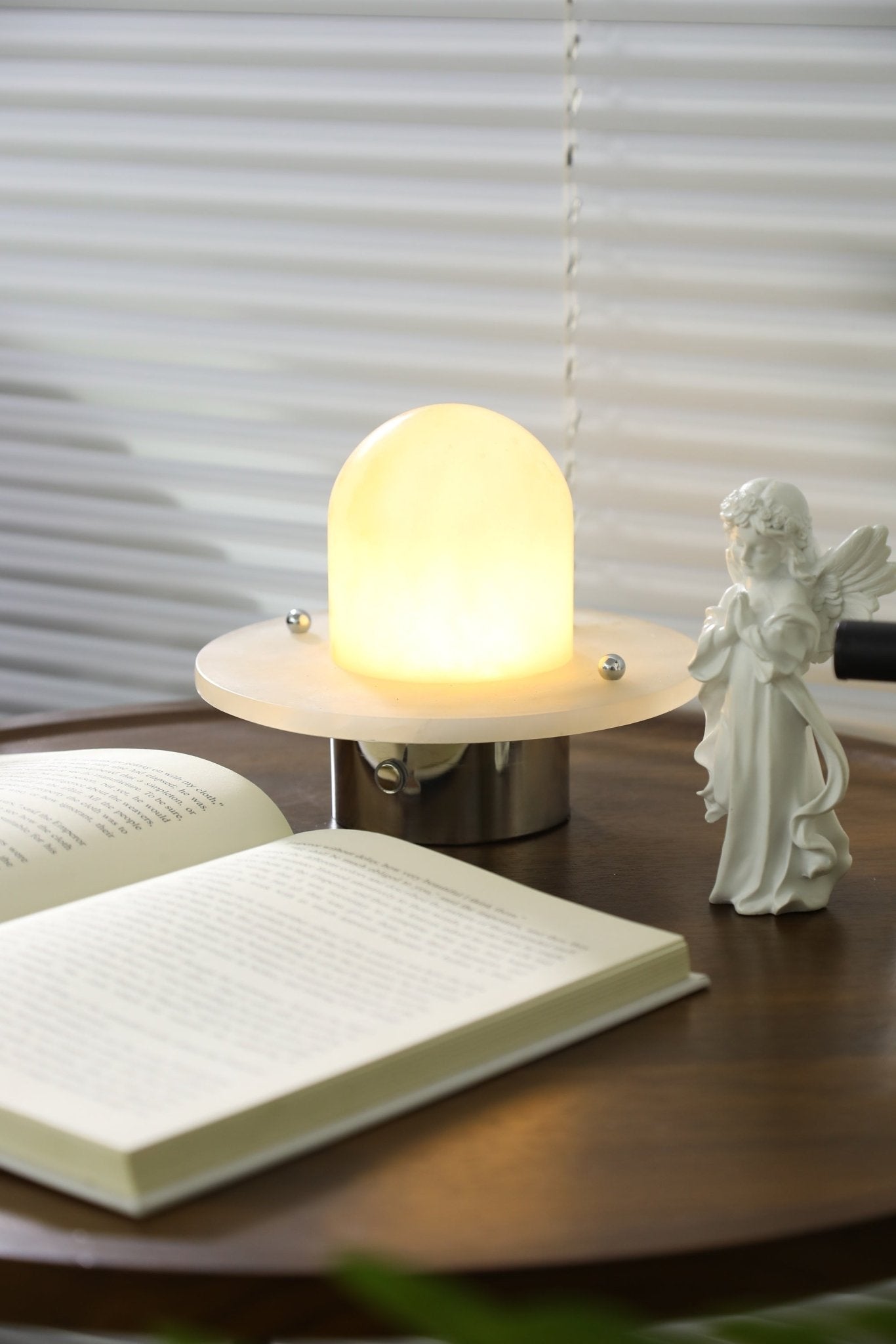 Clérachic Petrified lamp lit beside an open paperback, warm light on the timber surface.