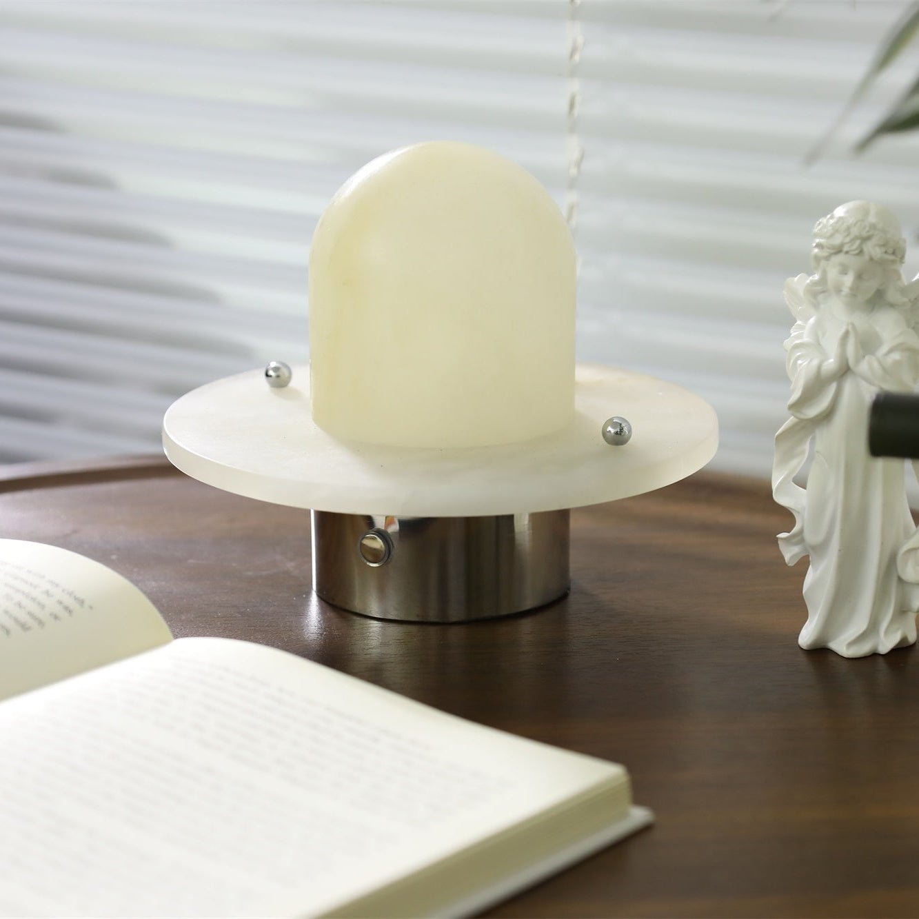 Clérachic Petrified table lamp unlit on walnut, pale dome catching soft window light.