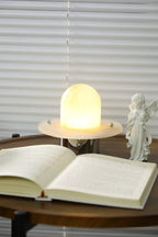 The Clérachic Petrified lamp lit on a round table, a warm pool of light across the pages.