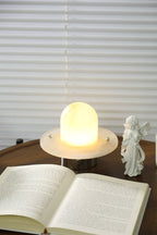 Clérachic Petrified table lamp lit beside an open book, cordless on a low reading table.
