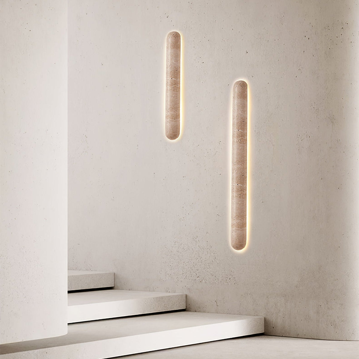 Two Clérachic travertine wall lights at different heights on a pale plaster wall, beside a flight of white steps.