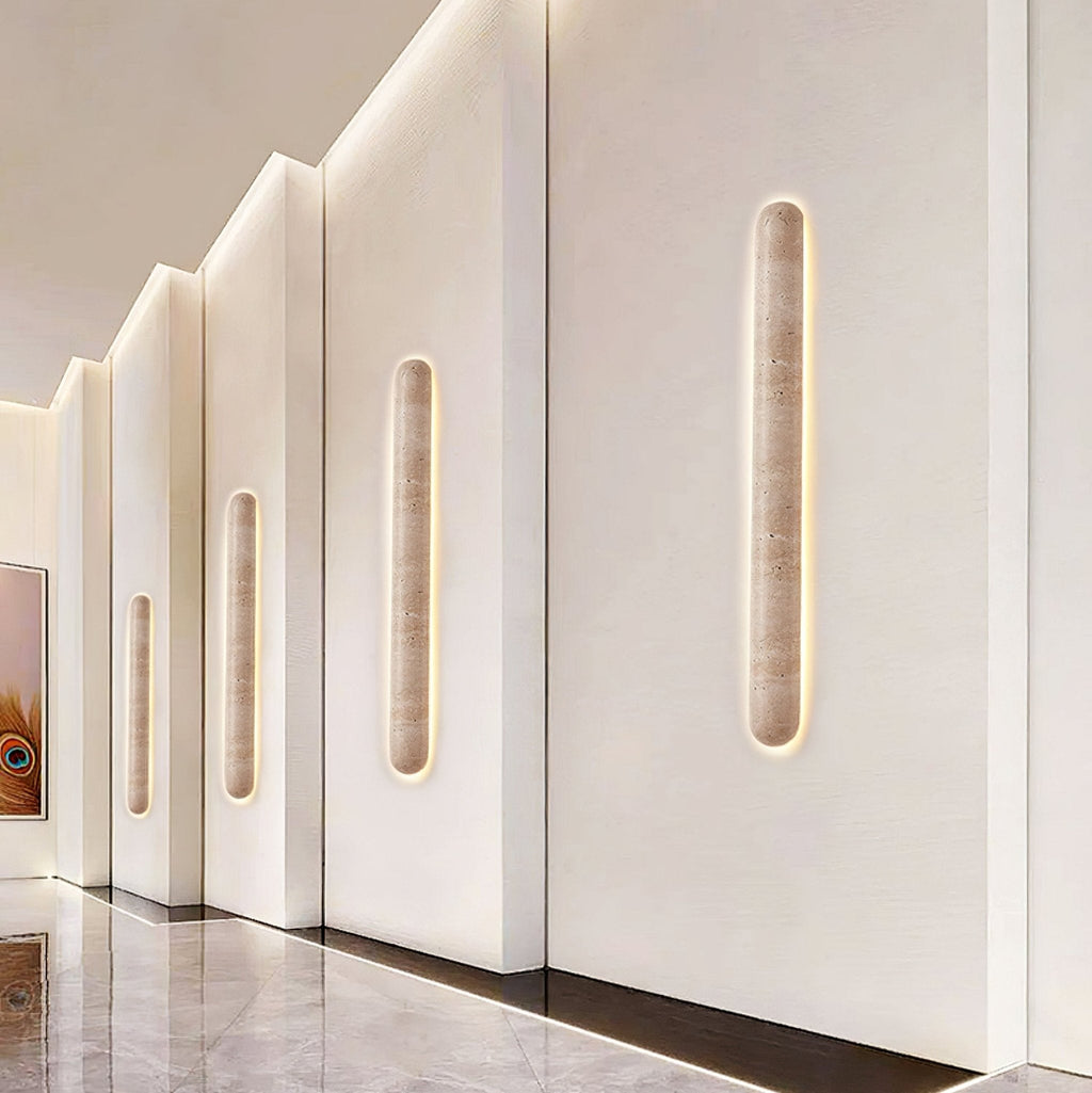 Row of Clérachic travertine wall lights set into stepped white panels along a hallway with a polished marble floor.