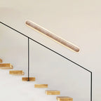 This Clérachic wall light mounted at a slant above a glass stair balustrade, with floating timber steps below.