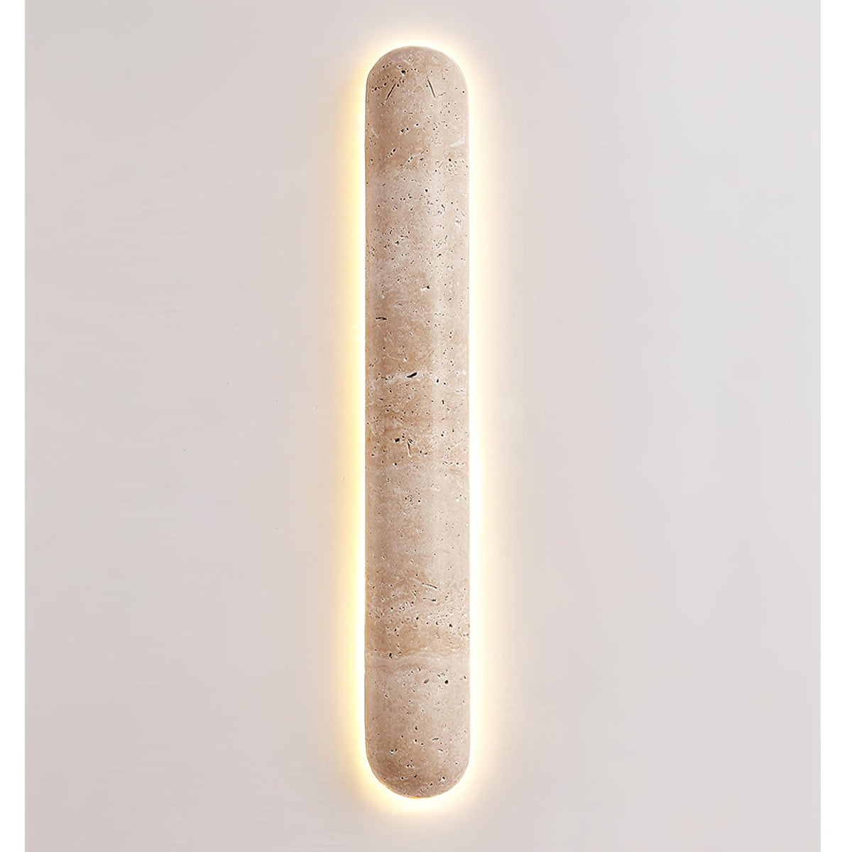 Lit Clérachic travertine wall light with a bright warm halo around its edge, on a plain light wall.
