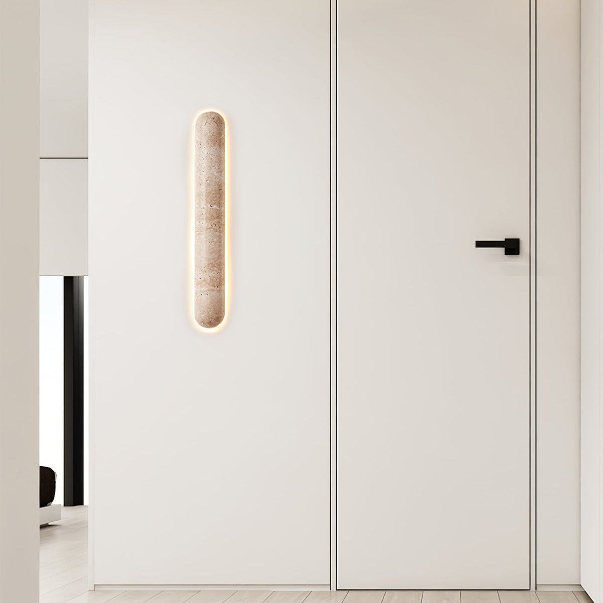 Small Clérachic wall light glowing on a white wall beside a flush door with a black handle.