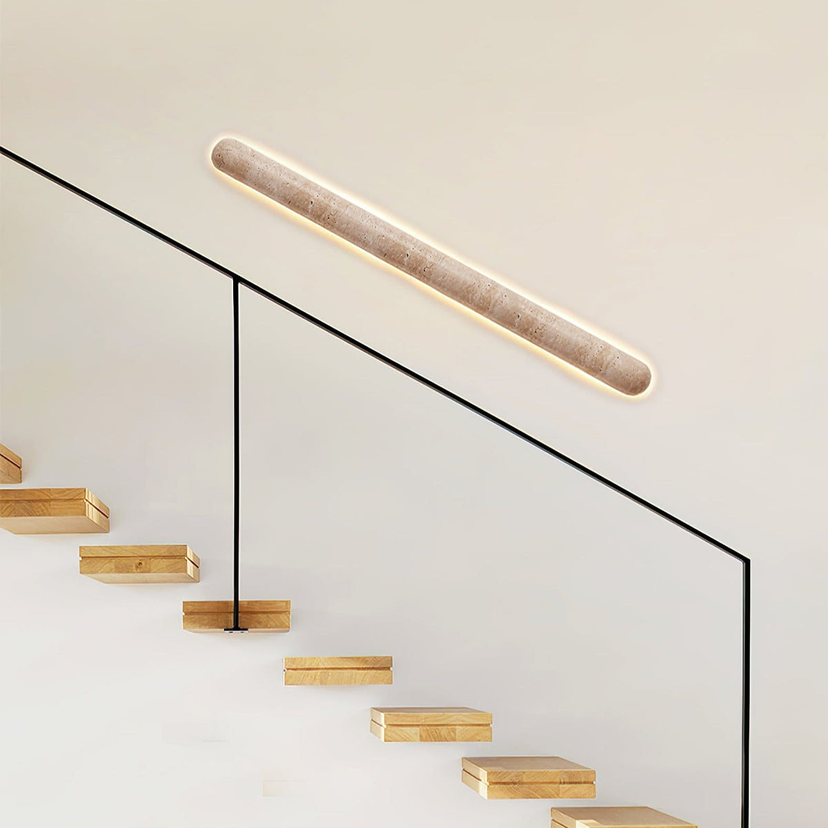 Angled Clérachic wall light above a glass stair rail, with wooden steps rising beneath it.