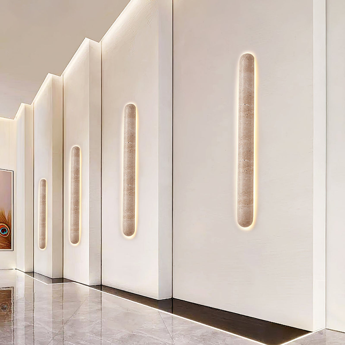 Several Clérachic wall lights of falling height lead along a white corridor wall with cove lighting overhead.