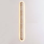 Very long, narrow Clérachic travertine wall light lit on a pale wall, with a thin glow along each side.