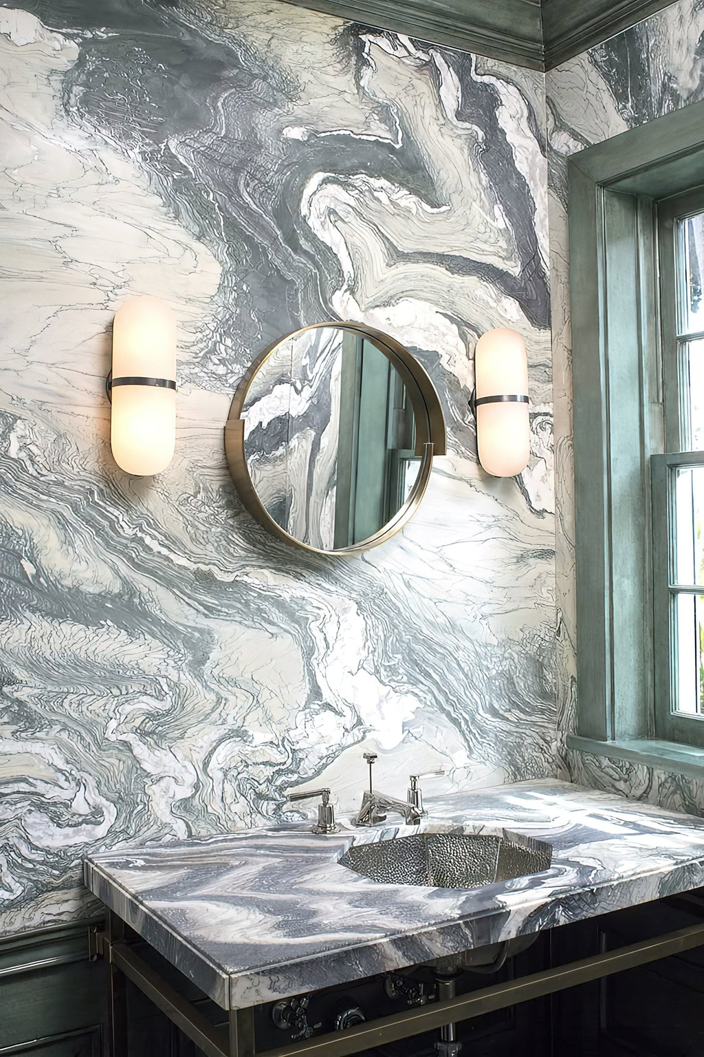 Clérachic Pill-Shaped Wall Sconce pair lit either side of a round mirror on a swirled marble wall, glowing amber white.