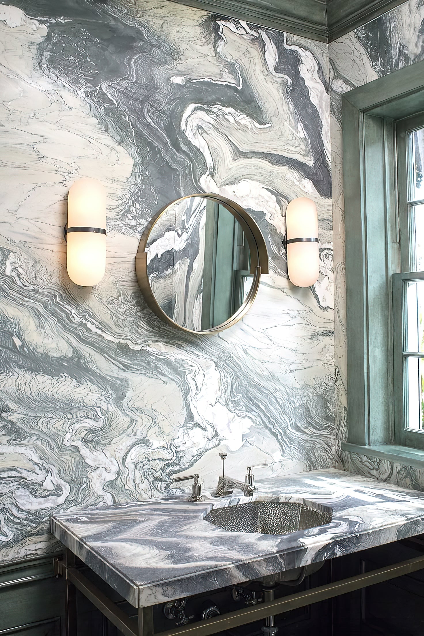 Clérachic Pill-Shaped Wall Sconce pair lit either side of a round mirror on a swirled marble wall, glowing amber white.