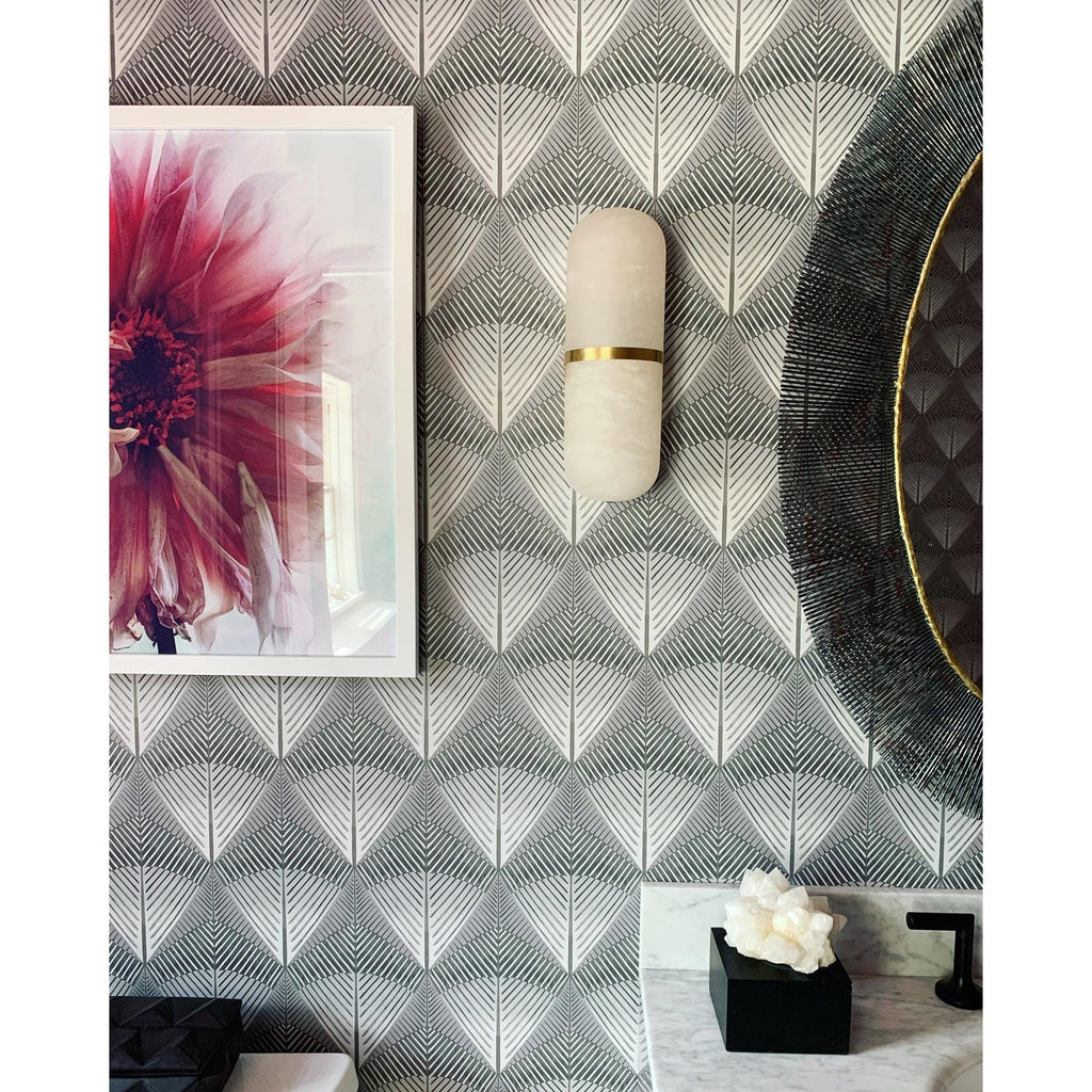 Clérachic Pill-Shaped Wall Sconce mounted on patterned deco wallpaper beside a framed floral print in a powder room.