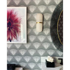 Clérachic Pill-Shaped Wall Sconce mounted on patterned deco wallpaper beside a framed floral print in a powder room.