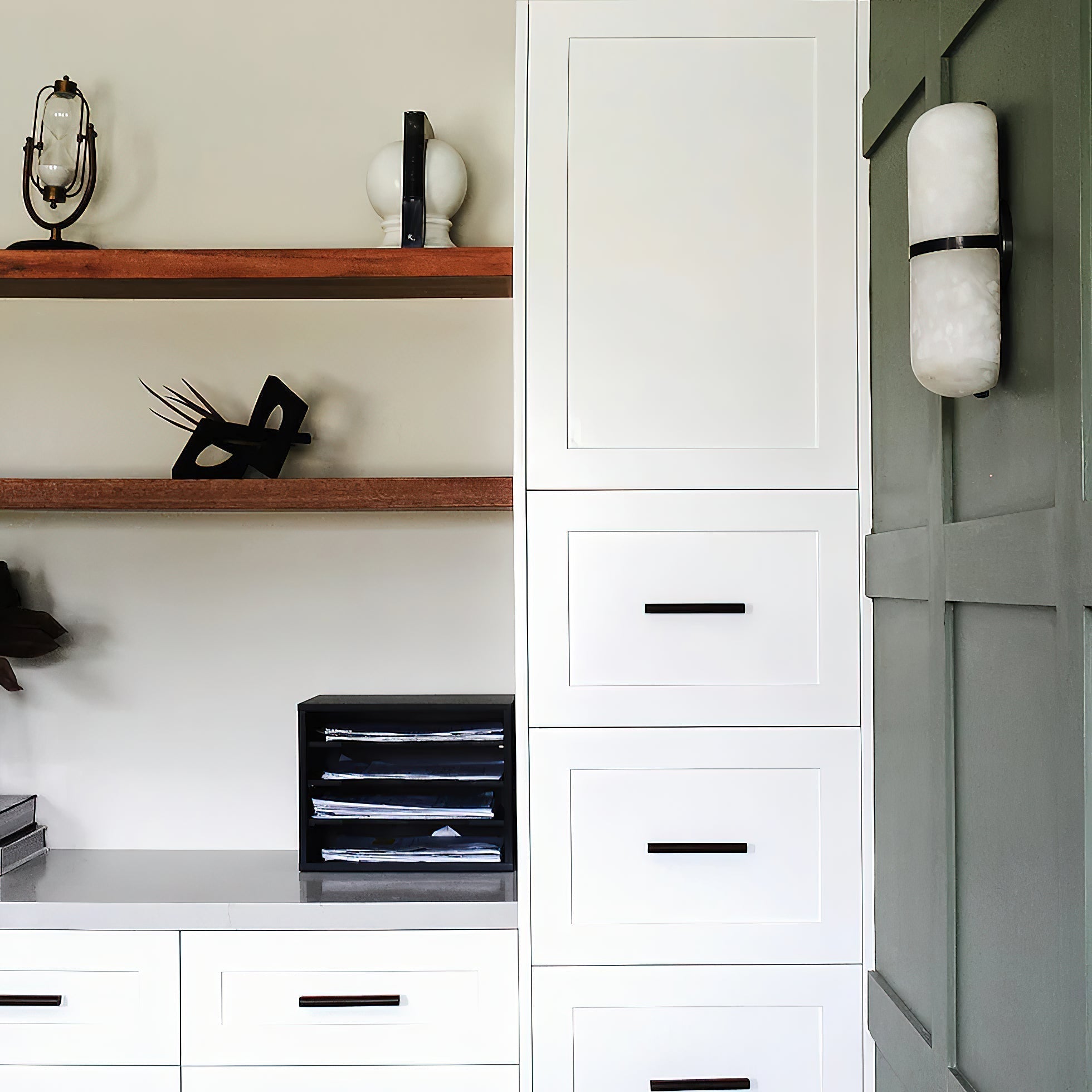 Clérachic Pill-Shaped Wall Sconce on a deep green panelled wall beside white cabinetry, alabaster bright against the paint.