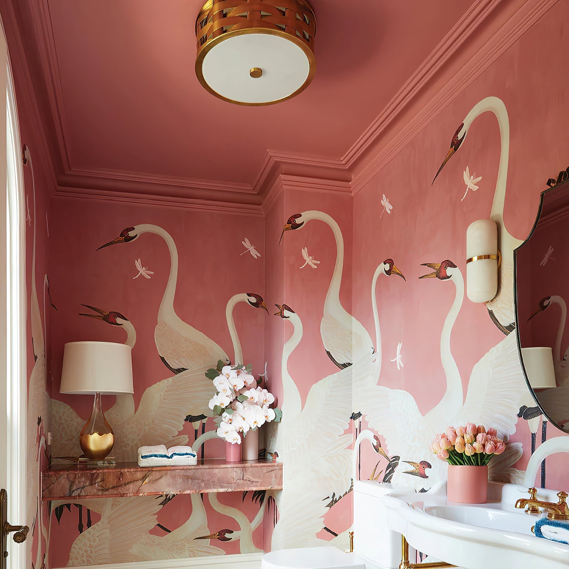 Clérachic Pill-Shaped Wall Sconce beside the mirror of a rose powder room, the pale stone lifting off a hand-painted mural.