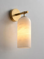 The Clérachic Pillar wall light lit on a pale wall, amber light banded across the alabaster.