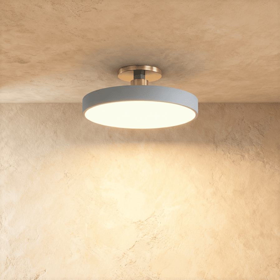 Clérachic ceiling light in grey, the flush-mount drum shade glowing warm white against a textured plaster wall.