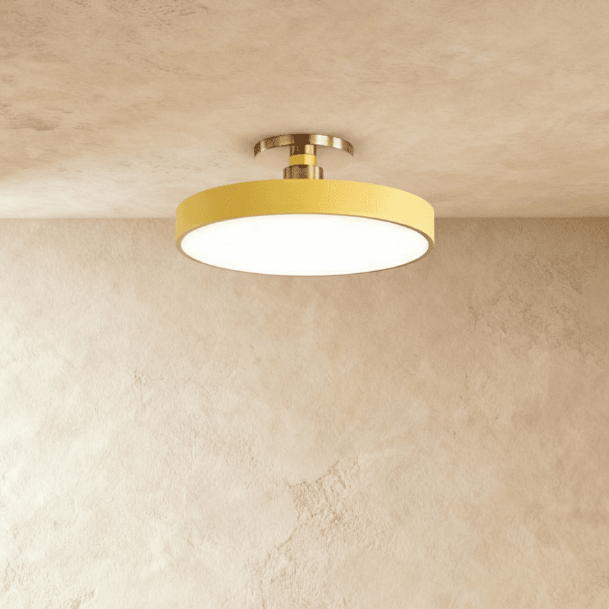 Clérachic ceiling light in yellow, the round drum diffuser glowing warm white on a brass ceiling stem.