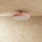 Clérachic ceiling light in pink with a nickel stem, its glowing drum shade set against a plaster ceiling.