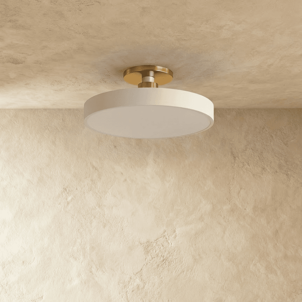 Clérachic ceiling light in white with a brass stem, the round drum shade glowing softly overhead.
