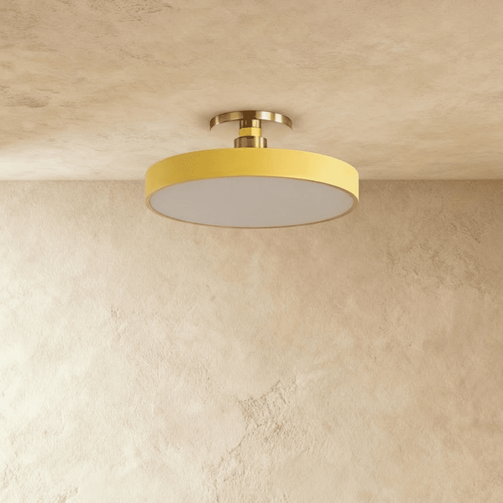 Clérachic ceiling light in yellow, its round drum diffuser glowing warm white beneath a plaster ceiling.