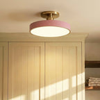 Clérachic ceiling light in pink mounted above a cream shaker cabinet, warm light falling across folded towels.