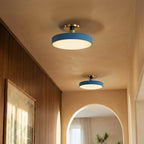 Clérachic ceiling lights in blue glow above a hallway, paired fixtures lighting the path toward an arched opening.