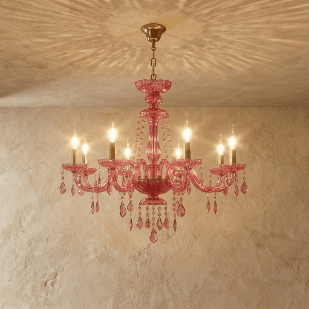 Clérachic pink crystal chandelier with eight brass candle arms and faceted crystal drops against a limewash wall.