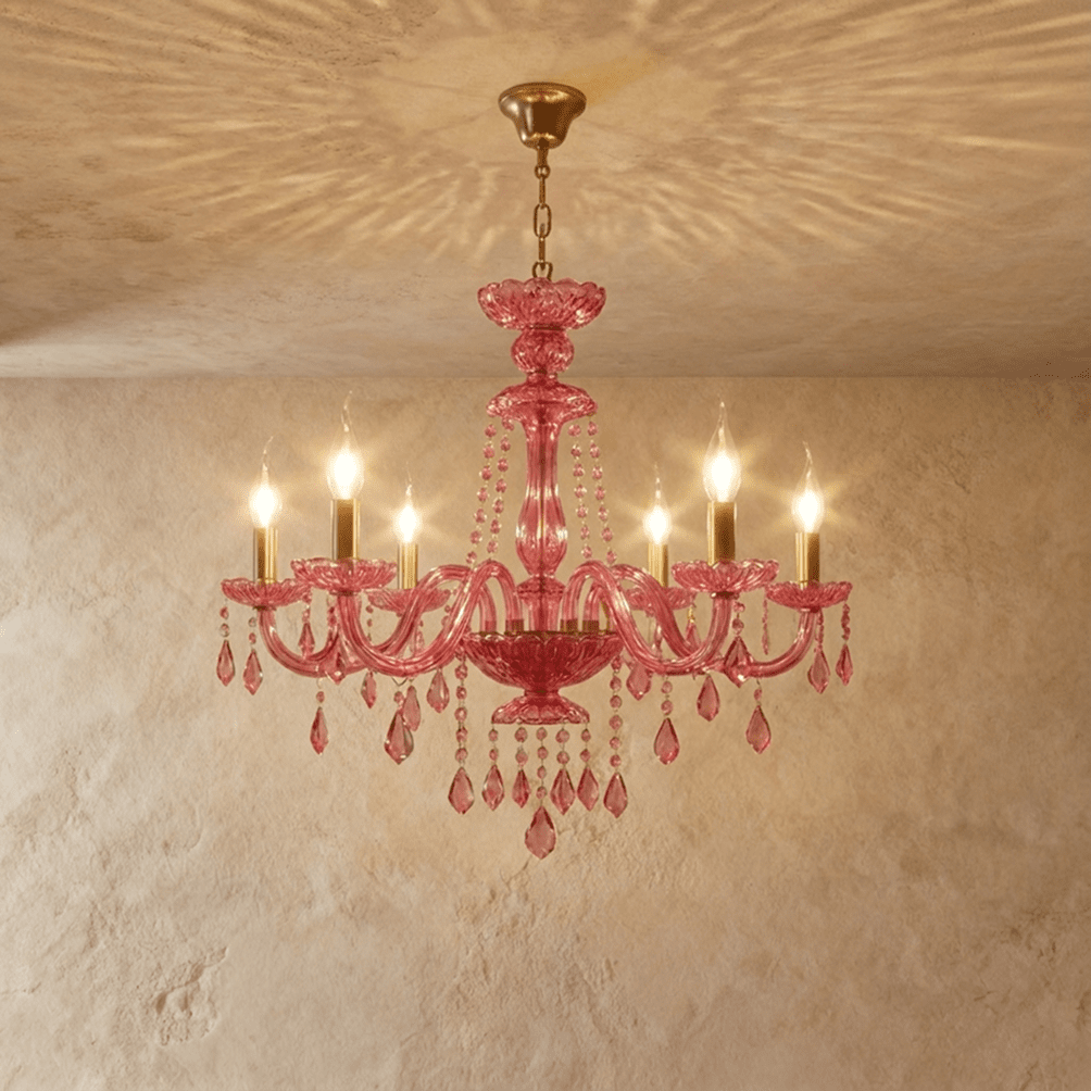 Clérachic pink crystal chandelier, six brass candle arms and crystal pendants, hung against a warm limewash wall.